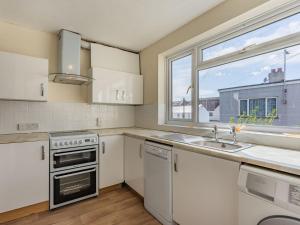 cocina con armarios blancos, fregadero y ventana en Sea Vista en Bognor Regis