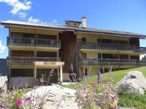budynek na wzgórzu z kwiatami przed nim w obiekcie Studio cosy avec mezzanine et balcon au pied des pistes - FR-1-297-158 w mieście Auris +8 zdjęć