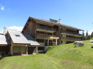 duży budynek na szczycie trawiastego wzgórza w obiekcie Studio cosy avec mezzanine et balcon au pied des pistes - FR-1-297-158 w mieście Auris