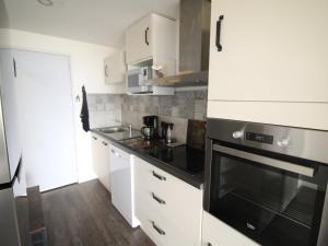 a kitchen with white cabinets and a black stove top oven at Appartement moderne 3 pièces, 6 couchages à 150m des pistes - FR-1-297-156 in Auris +8 photos