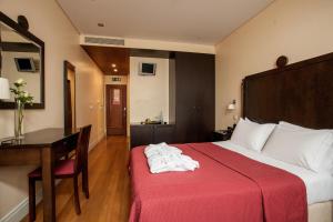 una camera d'albergo con un letto con una coperta rossa e una scrivania di Hotel Bracara Augusta a Braga