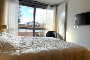 - une chambre avec un lit et une grande fenêtre dans l'établissement Modern Apt At The Foot Of The Slopes In Megève, à Megève