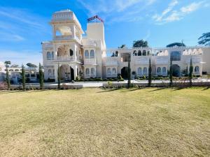 een groot wit gebouw met een gazon ervoor bij The Kumbha Mahal Resort in Kumbhalgarh