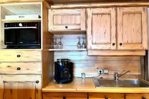 cocina con armarios de madera, fregadero y microondas en Chic And Cosy Apt With Balcony In Megeve en Megève
