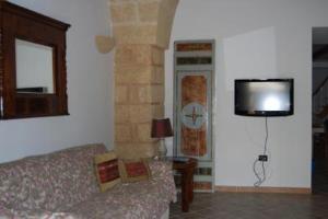 a living room with a couch and a flat screen tv at Casa Corte Giosuè Carducci in Specchia