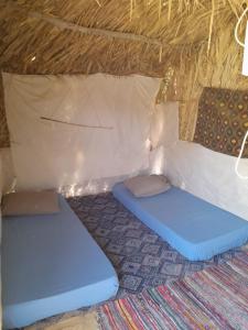 a room with two beds in a thatched tent at Hidigda Camp in ‘Izbat Ţanāţī