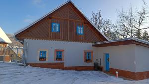 dom z drewnianym dachem w śniegu w obiekcie Apartmány stará škola w Swobodzie nad Upą