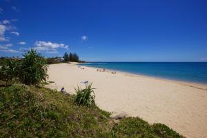 a beach with people sitting on the sand and the ocean at 23 Bryce St Moffat Beach in Caloundra