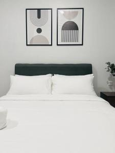 a bedroom with a white bed with three pictures on the wall at Urban Serviced Apartment in Bandar Penawar