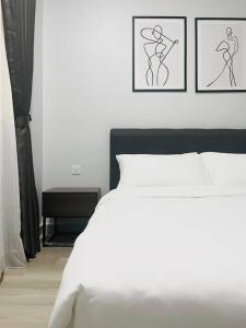 a bedroom with a white bed with two drawings on the wall at Urban Serviced Apartment in Bandar Penawar