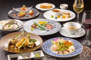 uma mesa com pratos de comida e copos de vinho em HOTEL BEACON ONOMICHI em Onomichi