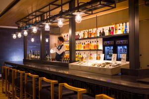 a bartender standing behind a bar in a restaurant at HOTEL BEACON ONOMICHI in Onomichi