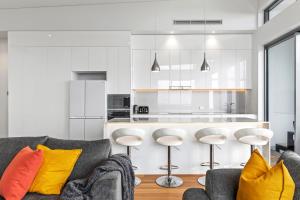 ein Wohnzimmer mit einem Sofa und einer Küche in der Unterkunft Absolute Beachfront 3 Bedroom Penthouse Bokarina Sunshine Coast in Kawana Waters