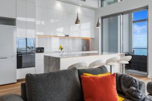 a living room with a gray couch and a kitchen at Absolute Beachfront 3 Bedroom Penthouse Bokarina Sunshine Coast in Kawana Waters