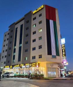 un gran edificio con una bandera a un lado en Onyx Hotel Apartments - MAHA HOSPITALITY GROUP en Ajman 