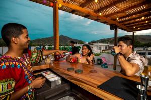 Hotel Boutique CASA CHUNUU Santa Marta في سانتا مارتا: مجموعة من الناس يجلسون في حانة