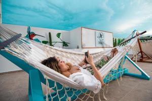 a woman laying in a hammock with her phone at Hotel Boutique CASA CHUNUU Santa Marta in Santa Marta