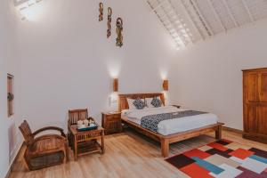 a bedroom with a bed and a chair at Dream Beach Huts in Nusa Lembongan