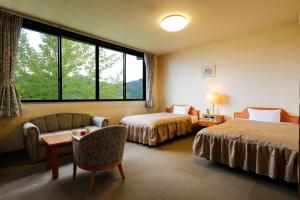 una camera d'albergo con due letti e una finestra di たまご肌美人の湯　美榛苑 a Uda