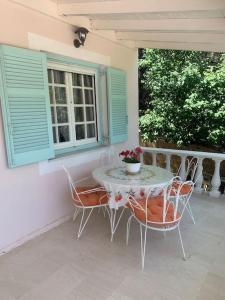 a table and chairs on a porch with a window at Holiday house near the beach - 2 in 1 in Perítheia