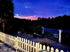 a white picket fence in a yard with a sunset at Holiday house near the beach - 2 in 1 in Perítheia