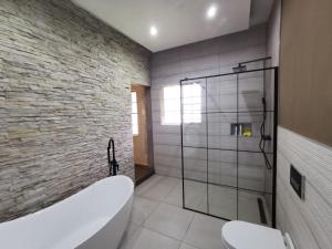 Das Bad ist mit einer Badewanne und einer Glasdusche ausgestattet. in der Unterkunft Blackwood Eco Lodge in Witbank