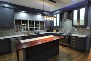 a kitchen with black cabinets and a wooden counter top at Blackwood Eco Lodge in Witbank