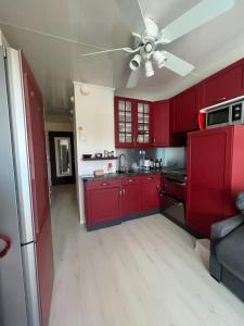 a kitchen with red cabinets and a ceiling fan at La désirade full south in La Ciotat