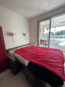 a bedroom with a bed with a red comforter at La désirade full south in La Ciotat