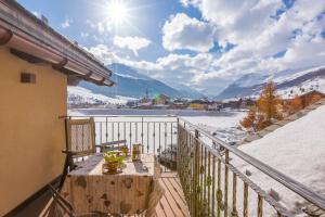 a balcony with a table and snow covered mountains at Danubio - Happy Rentals in Livigno