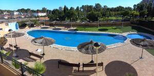 einen Pool mit Sonnenschirmen und einen Golfplatz in der Unterkunft Costa Azahar II Nº 1041 in Oropesa del Mar