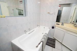 a white bathroom with a tub and a sink at 139 Longships - Cozy Double Room in Plettenberg Bay