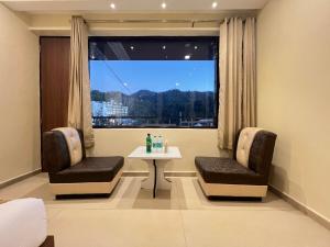 a room with two chairs and a table and a window at Hotel White Orchid Dalhausie in Dalhousie