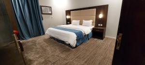 a bedroom with a large bed with blue curtains at Hmm Serviced Apartments in Al Kura