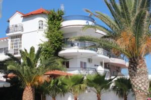 a white building with palm trees in front of it at Elarin studios & apartments in Faliraki