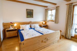 a bedroom with a wooden bed and two windows at Haus Huis'n in Grainau