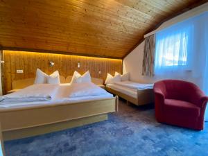 a hotel room with two beds and a red chair at Appartement Hubner in Ramsau am Dachstein