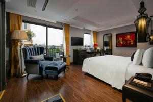 a bedroom with a bed and a chair and a television at Hanoi L'Heritage Hotel & Gym - Spa in Hanoi