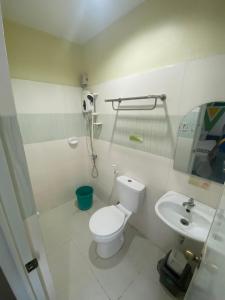 a white bathroom with a toilet and a sink at BOPEMPC Safari Hostel in Tagbilaran City