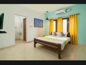 1 dormitorio con 1 cama grande y cortinas amarillas en Tharayil Apartments en Kochi