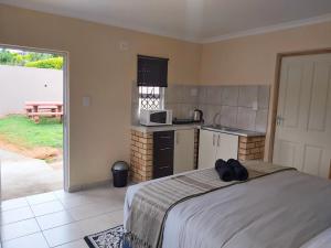 a bedroom with a bed and a kitchen with a microwave at Ezweni Lodge in Inanda