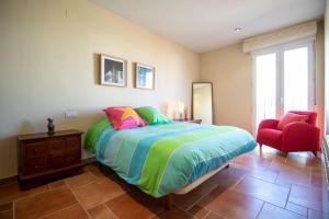 1 dormitorio con 1 cama grande y 1 silla roja en Piso con vista espectacular en Vistabella, en Vistabella del Maestrazgo