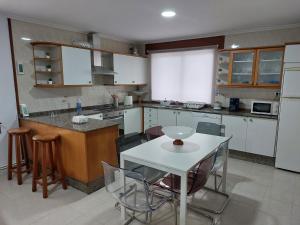 a kitchen with white cabinets and a white table and chairs at Acogedora Casa de campo- BAJO con finca- in Neda +17 photos