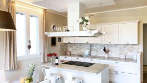 una cucina con armadi bianchi e lavandino di Falconetta Luxury House a Portoferraio