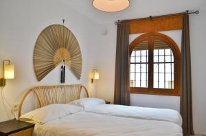 two beds in a room with a window and a fan at SunShine Almanzor in Córdoba