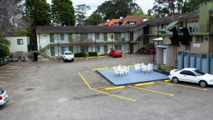 a parking lot in front of a building with white statues at Ascot Motor Inn in Hornsby