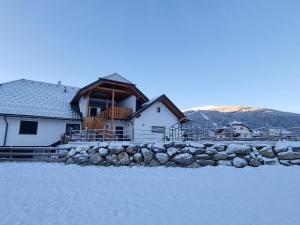 a house with a stone fence in the snow at Das Dorfnest in Sankt Margarethen im Lungau