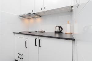 a kitchen with white cabinets and a black counter top at Apartment Beachy Dream by Renters in Gdańsk