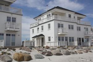 a large white building on the beach with rocks at Ostseeperle in Kappeln