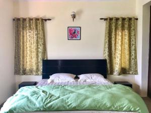 BhowāliにあるWinged Villa A7のベッドルームに緑の掛け布団付きのベッド1台